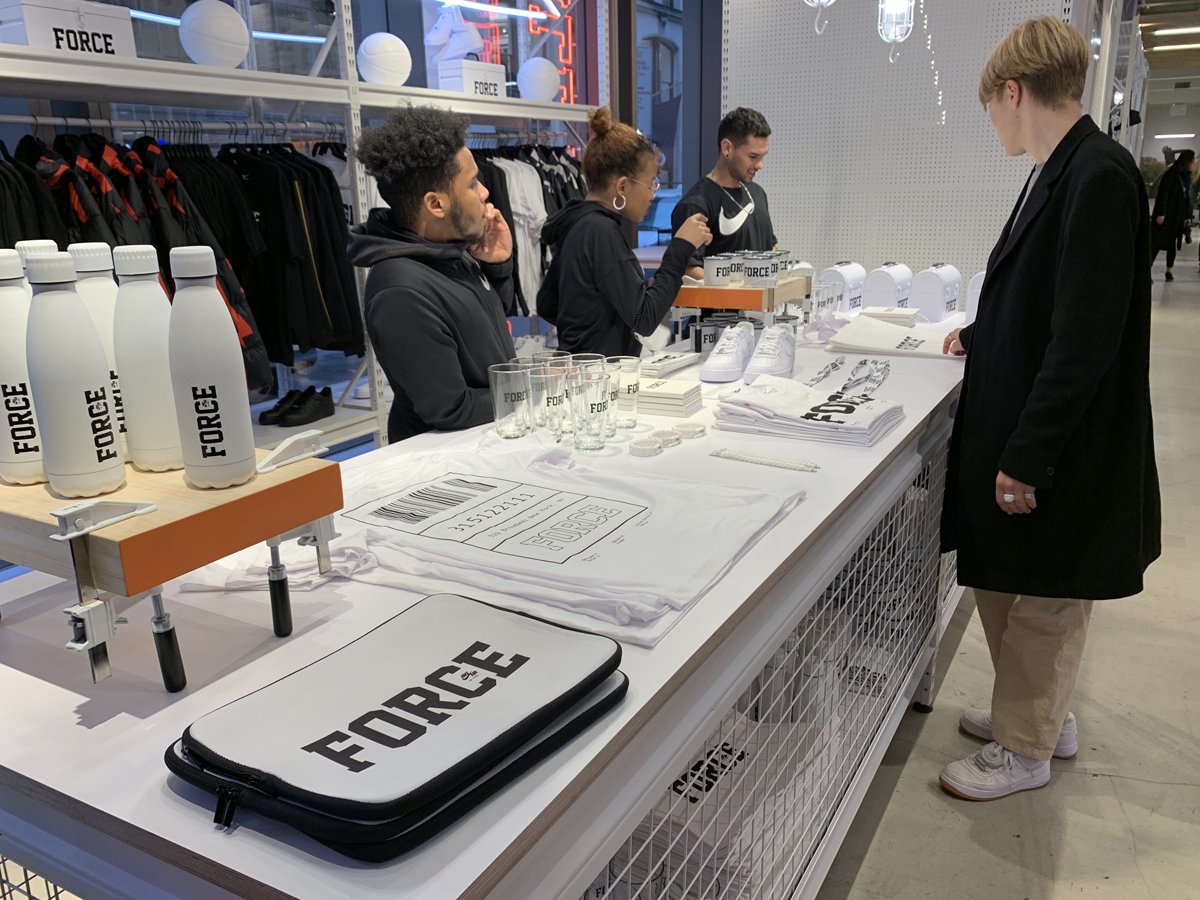 Nike SOHO store display with FORCE water bottles and bags on a table