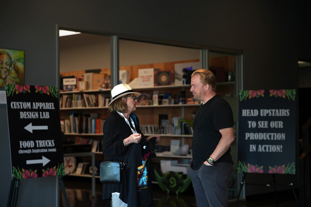 two people talking at The Backstage branded merchandise event