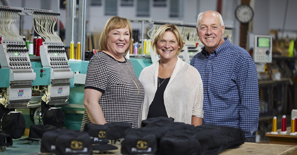 Kate Ivory from GIDI Promotions with Juli Cordill and Chris Feryn from Premier Press in front of an embroidery machine